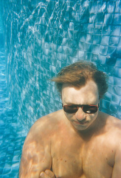 Man Swimming Underwater in a Pool During Daytime