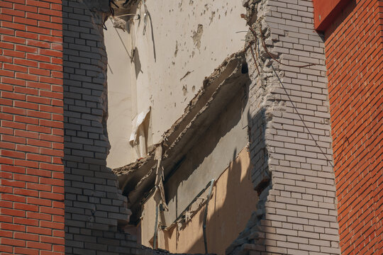 Close-up of a large hole in a residential brick wall caused by an explosion blast wave or shrapnel.