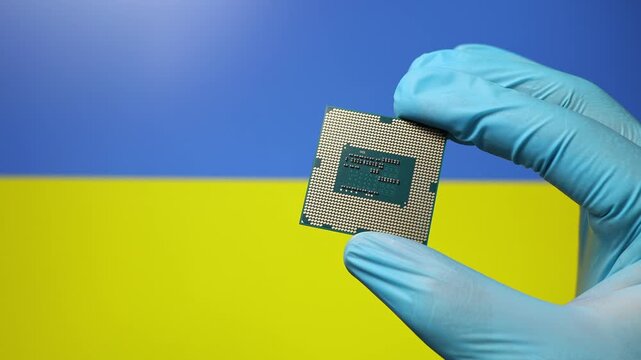 Close up view of hand in blue glove holding CPU microchip. Ukrainian flag in blurred background. Concept of semiconductor shortage and artificial intelligence development in Ukraine.