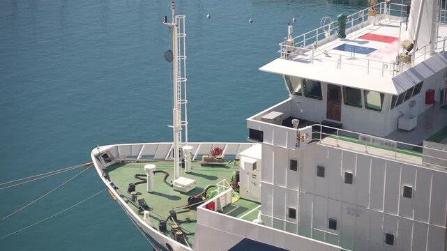 High angle view of a moored cargo ship bow, calm blue water of coastal harbor