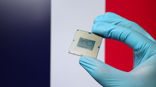 Close up view of hand in blue glove holding CPU microchip. French flag in blurred background. Concept of semiconductor shortage and artificial intelligence development in France.
