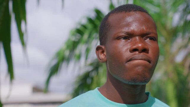 Man speaks with slight head movements against outdoor background of greenery. close up shots focus on his upper body and facial expressions set in natural environment