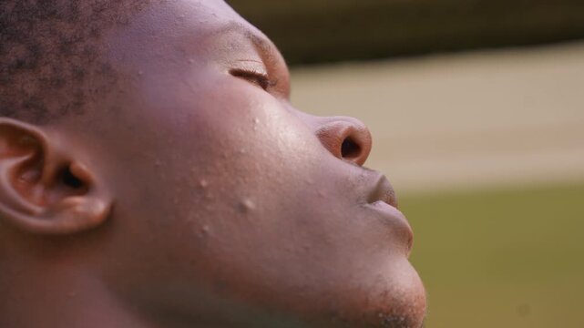 Close up view focusing on side angle details including ear nose mouth of man face with visible skin texture and facial features. background remains softly blurred throughout