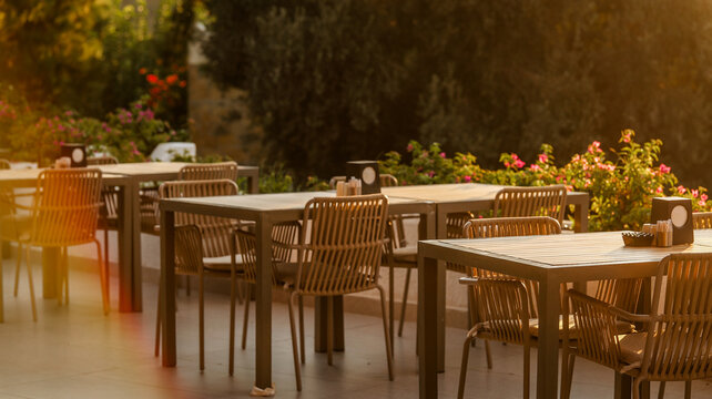 Outdoor restaurant terrace with modern wicker chairs and tables at sunset golden hour light