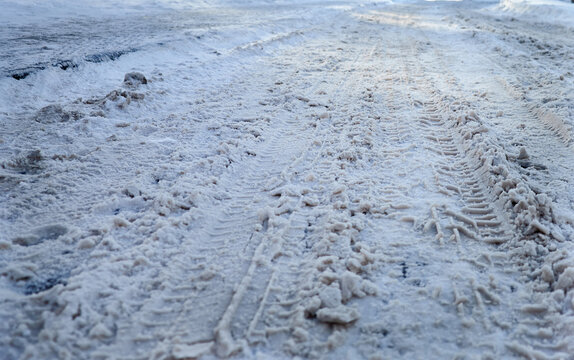 Slushy icy road surface with melting snow, deep puddles and dirty ice after winter thaw. Hazardous slippery street conditions, seasonal weather and urban winter background
