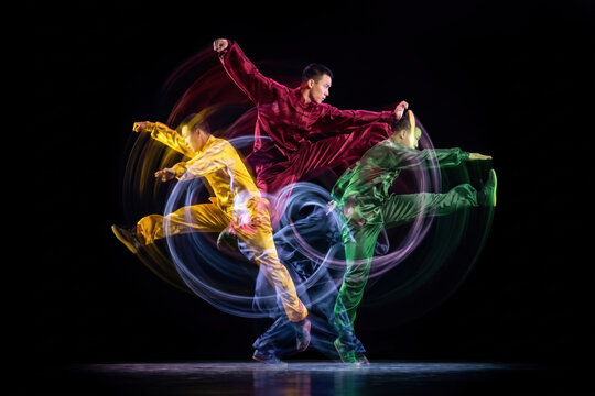 Dynamic dancer holds handstand freeze with colorful motion trails. Concept of dance event posters, music media, youth culture ads and festival visuals.