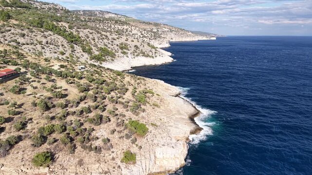 Cinematic horizontal aerial drone footage of the rugged rocky coastline and deep blue Aegean sea near Giola in Thassos, Greece &ndash; 2026