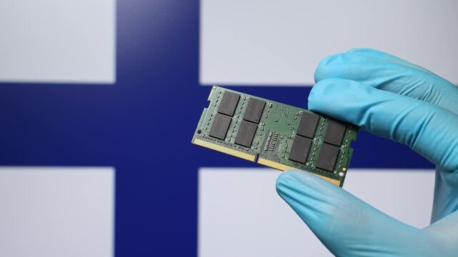 Close up view of hand in blue glove holding RAM memory microchip module. Finnish flag in blurred background. Concept of semiconductor shortage, artificial intelligence development in Finland.