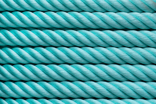 Close-up of parallel turquoise ropes with twisted fiber texture forming a uniform decorative pattern.