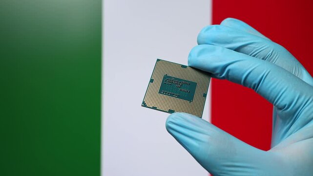 Close up view of hand in blue glove holding CPU microchip. Italian flag in blurred background. Concept of semiconductor shortage and artificial intelligence development in Italy.