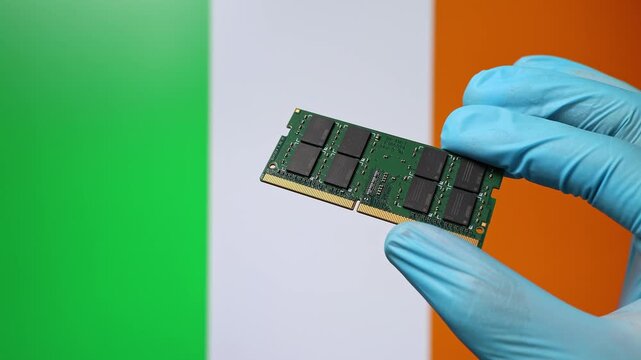 Close up view of hand in blue glove holding RAM memory microchip module. Irish flag in blurred background. Concept of semiconductor shortage, artificial intelligence development in Ireland.