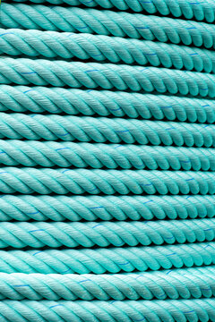 Close-up of parallel turquoise ropes with twisted fiber texture forming a uniform decorative pattern.