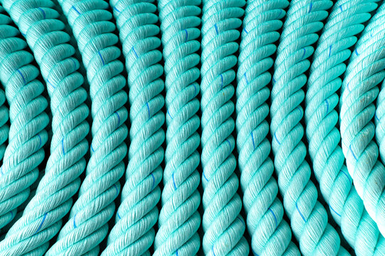 Close-up of parallel turquoise ropes with twisted fiber texture forming a uniform decorative pattern.