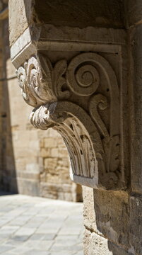 Historic carved limestone architectural corbel on ancient palazzo facade in sunlight