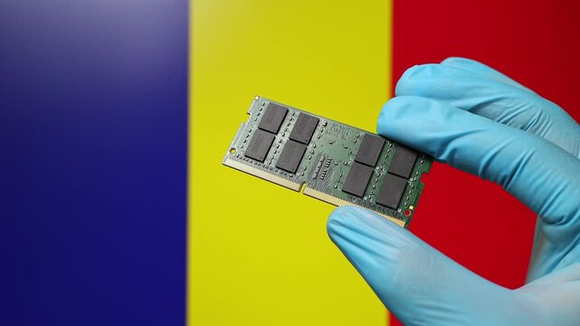 Close up view of hand in blue glove holding RAM memory microchip module. Romanian flag in blurred background. Concept of semiconductor shortage, artificial intelligence development in Romania.