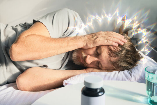Man suffering from painful migraine with aura, holding his head in his hands