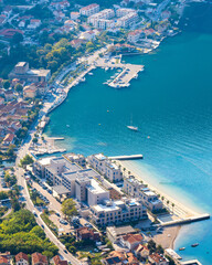 Fototapeta premium Aerial high-angle view of Risan town in Kotor Bay, Montenegro in soft early morning light, featuring coastal architecture, harbor, and calm blue Adriatic sea.