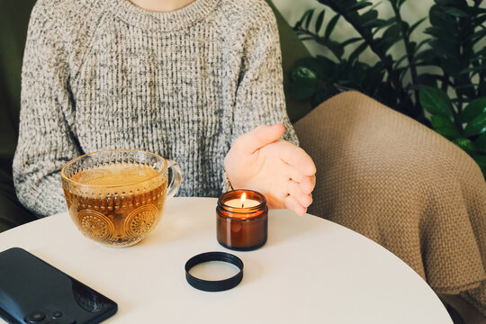 Woman enjoying cozy evening with tea and candlelight