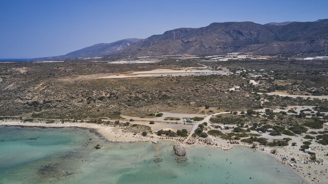 Overtourism, A beach with clear water, surrounded by a wide, dry landscape and mountains in the background, Elafonissi, lagoon, south-west tip of Crete, Crete, Greek Islands, Greece