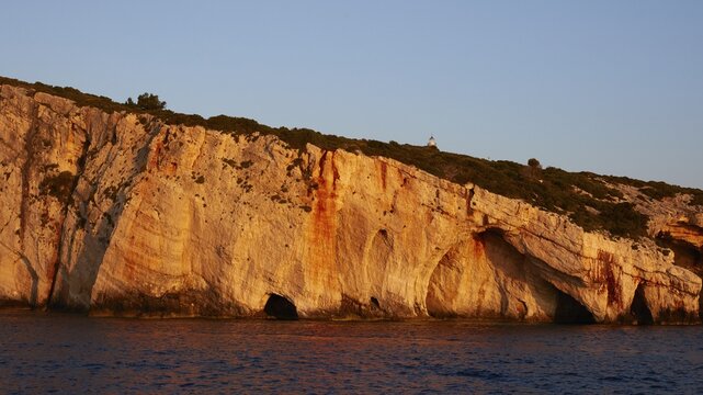 Blue Caves, morning light, lighthouse, rocky coast, blue cloudless sky, northeast coast, Zakynthos Island, Ionian Islands, Greece