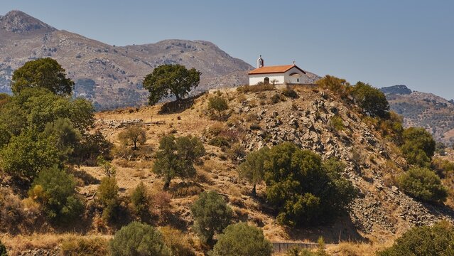 A small chapel perches on a hill surrounded by trees in a mountainous landscape, Amari Basin, Amari, Central Crete, Greek Islands, Greece
