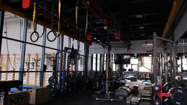 Wide interior view of a modern functional training gym with suspension rings, strength machines and workout stations, suitable for cross training, fitness business, athletic performance, conditioning 