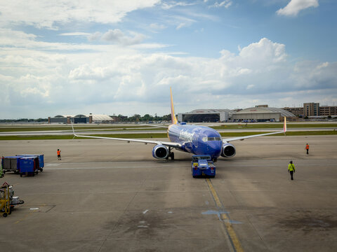 LOUISVILLE, KY, JUN 9, 2026: Close three-quarter view of a Southwest Boeing 737 on pushback with a tug and ramp workers, and hangars behind under puffy clouds at Louisville Muhammad Ali International 