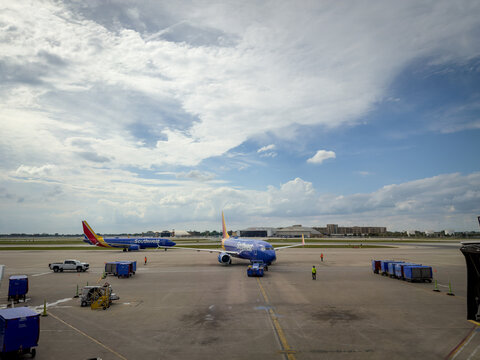 LOUISVILLE, KY, JUN 9, 2026: Two Southwest 737s on the airport ramp, one on pushback and another taxiing behind it, with a pickup truck, baggage carts and dramatic clouds