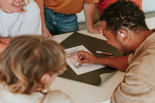 Hand colouring a student loan debt payoff grid on a textured green sheet, a natural morning scene for household budget and financial planning