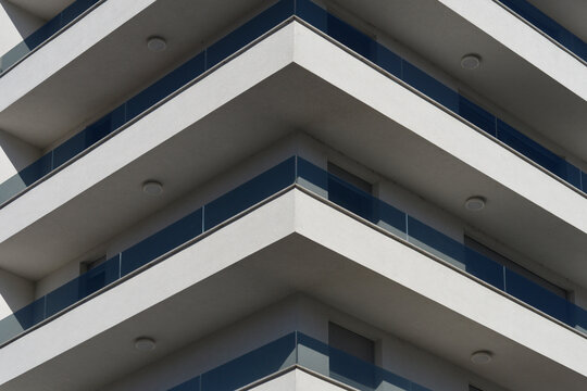 Architectural detail of a residential building facade featuring sharp corner balconies with dark tinted glass railings.