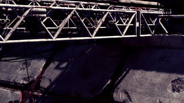 Rusty metal beams and tangled wires create an industrial scene in an abandoned location. Shadows linger as nature begins to weave through the remnants of human craftsmanship.