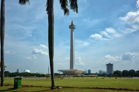 Indonesia, Jakarta &ndash; December 12, 2025: Monas tower rising above Merdeka Square, framed by palm trees under a bright blue sky, Indonesia&rsquo;s iconic landmark
