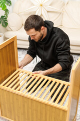 Young man assembling furniture in  living room. Concept of home improvement, © Olga Mukashev