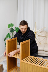Young man assembling furniture in  living room. Concept of home improvement, © Olga Mukashev