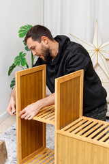 Young man assembling furniture in  living room. Concept of home improvement, © Olga Mukashev