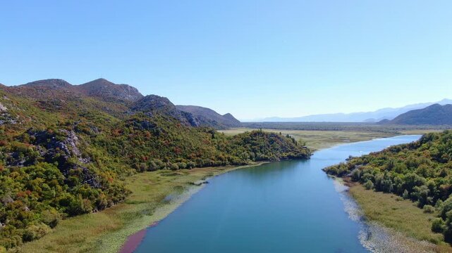 Breathtaking cinematic drone footage flying over the vast pristine waters and lush green mountain shores of Lake Skadar National Park in Montenegro
