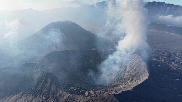 Smoky volcanic crater at Mount Bromo with steam plumes and textured ash slopes.