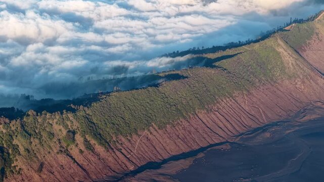 Mist shrouds volcanic slopes at dawn. Lush greenery climbs rugged, reddish terrain