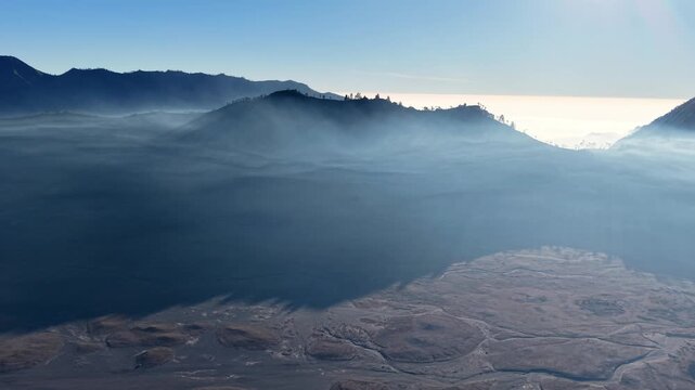 Mist wraps around mountain peaks and valleys below near Bromo