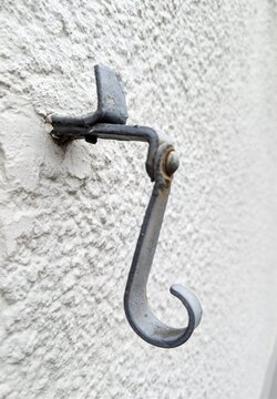 Vintage forged iron shutter hook mounted on textured white wall