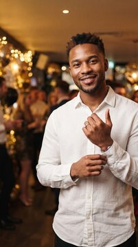 Smiling Man Adjusting Cufflinks at a Festive Evening Gathering with Bokeh Lights