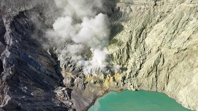 Aerial drone view of Mount Ijen crater with sulfur fumaroles and vivid turquoise acidic lake