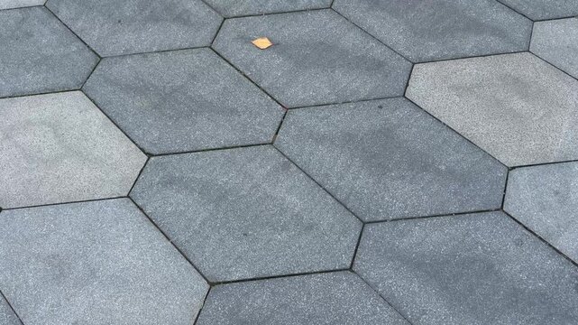 Close up of grey hexagonal paving stones on a city pedestrian walkway outdoors. Paving stones, hexagonal pavement, pedestrian walkway, grey tiles.