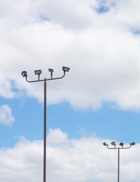 Outdoor commercial LED parking lot light pole with multiple LED flooding and bullhorn brake agains and blue and cloudy sky.  Vertical frame
