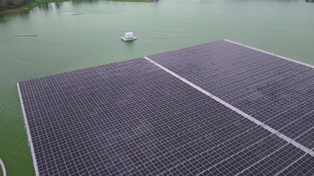 Drone aerial shot of large floating solar PV array on calm reservoir water.