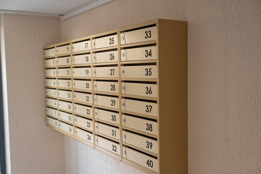 Numbered metal mailboxes mounted on the wall in the shared entrance of an apartment building