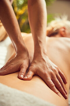 Therapist hands massaging woman's lower back at spa