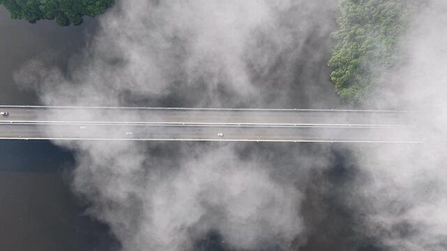 Dense fog blankets the bridge, hiding nearby trees and water at Tasik Raban