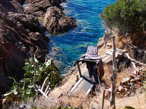 Turquoise cove with wild cactus and abandoned treadmill in Corsica