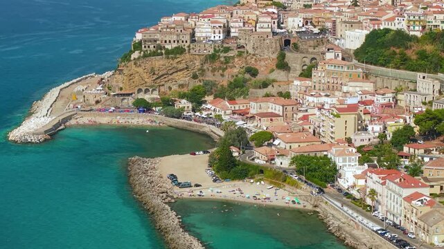Pizzo Calabria Italy 4k drone view of coastline breakwaters to castle on cliff. Tilt up flyover of turquoise sea coves, historic town and elevated viaduct bridge b-roll establishing scenic footage